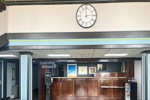 A reception area with a wall-mounted clock, a check-in kiosk, and a counter with a beverage dispenser. - 1 King Bed | Non-Smoking, Micfridge (Fremont (OH))
