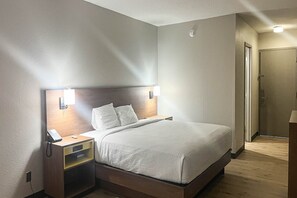 Une chambre d’hôtel équipée d’un lit, de tables de chevet, d’un téléphone et d’un luminaire fixé au mur.