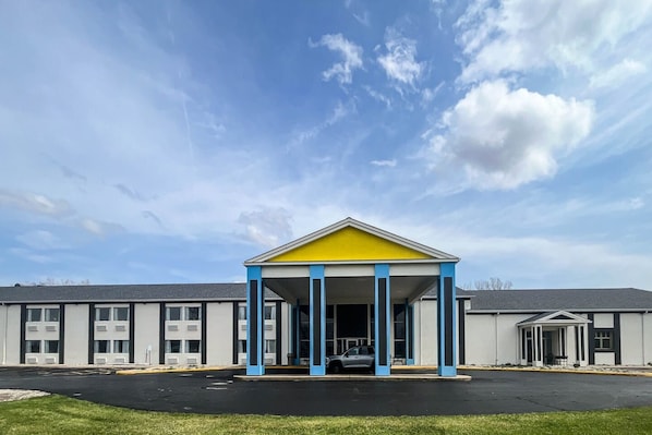 Un bâtiment avec un toit jaune et des colonnes bleues, un parking et un ciel dégagé.