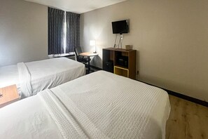 Une chambre d’hôtel avec deux lits, un bureau, une chaise, une télévision et une armoire.