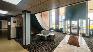 A lobby with a reception desk, seating area, and a glass door entrance.