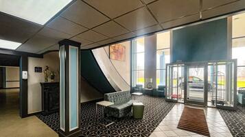 A lobby with a reception desk, seating area, and a glass door entrance.