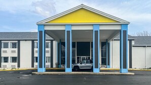 A building with a covered entrance, columns, and a parked car.