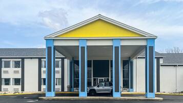 A building with a covered entrance, columns, and a parked car.