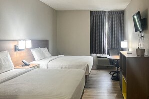 Une chambre d’hôtel avec deux lits, un bureau avec une chaise, une télévision et une fenêtre avec des rideaux.