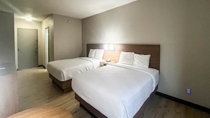 A hotel room with two beds, a wooden headboard, a bedside table with a phone, and a door leading to another room. - 2 Queen Beds | Non-Smoking, Micfridge (Fremont (OH))