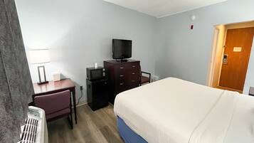 A hotel room with a bed, a desk, a television, and a dresser.