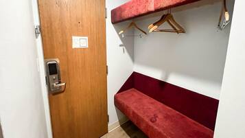 A room with a wooden door, a red bench, and a wall-mounted rack with hangers.