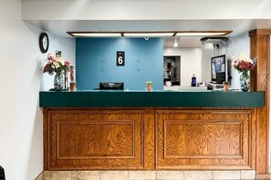 A reception desk with a blue wall, a clock, and a number sign.