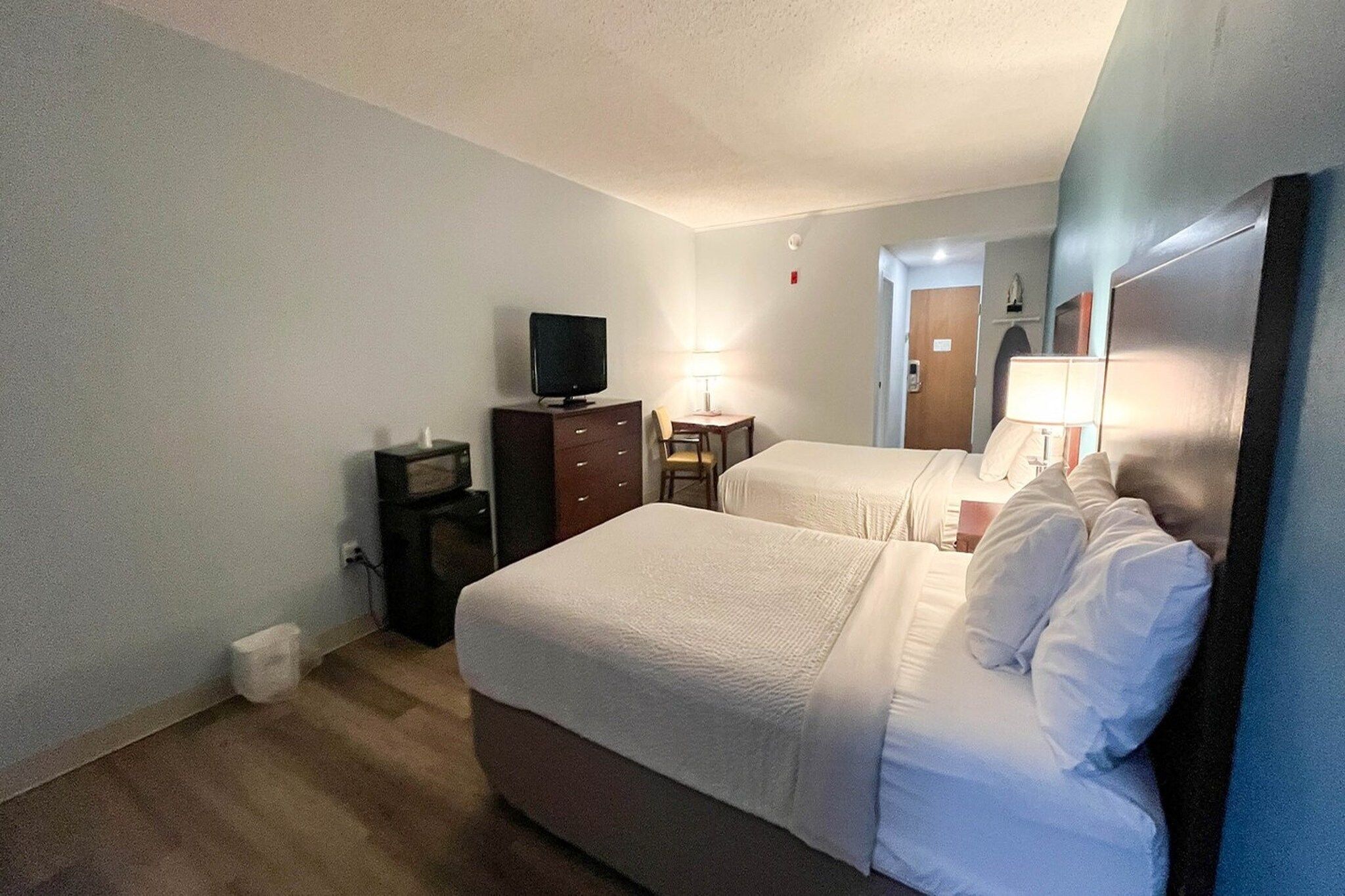 A hotel room with two beds, a television, a desk, and a lamp.