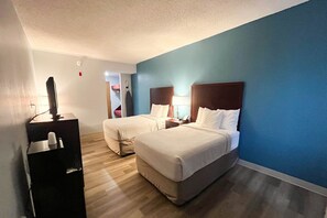 A hotel room with two beds, a desk, and a television.