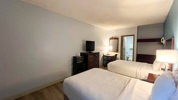 A hotel room with two beds, a television, a desk, and a mirror.
