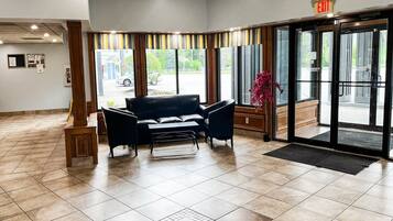 A lobby with a reception desk, a black leather sofa, and a large glass door leading outside.