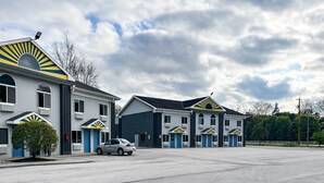 A motel with multiple units, a parking lot, and a clear sky.