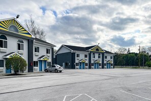 A motel with multiple units, a parking lot, and a clear sky.