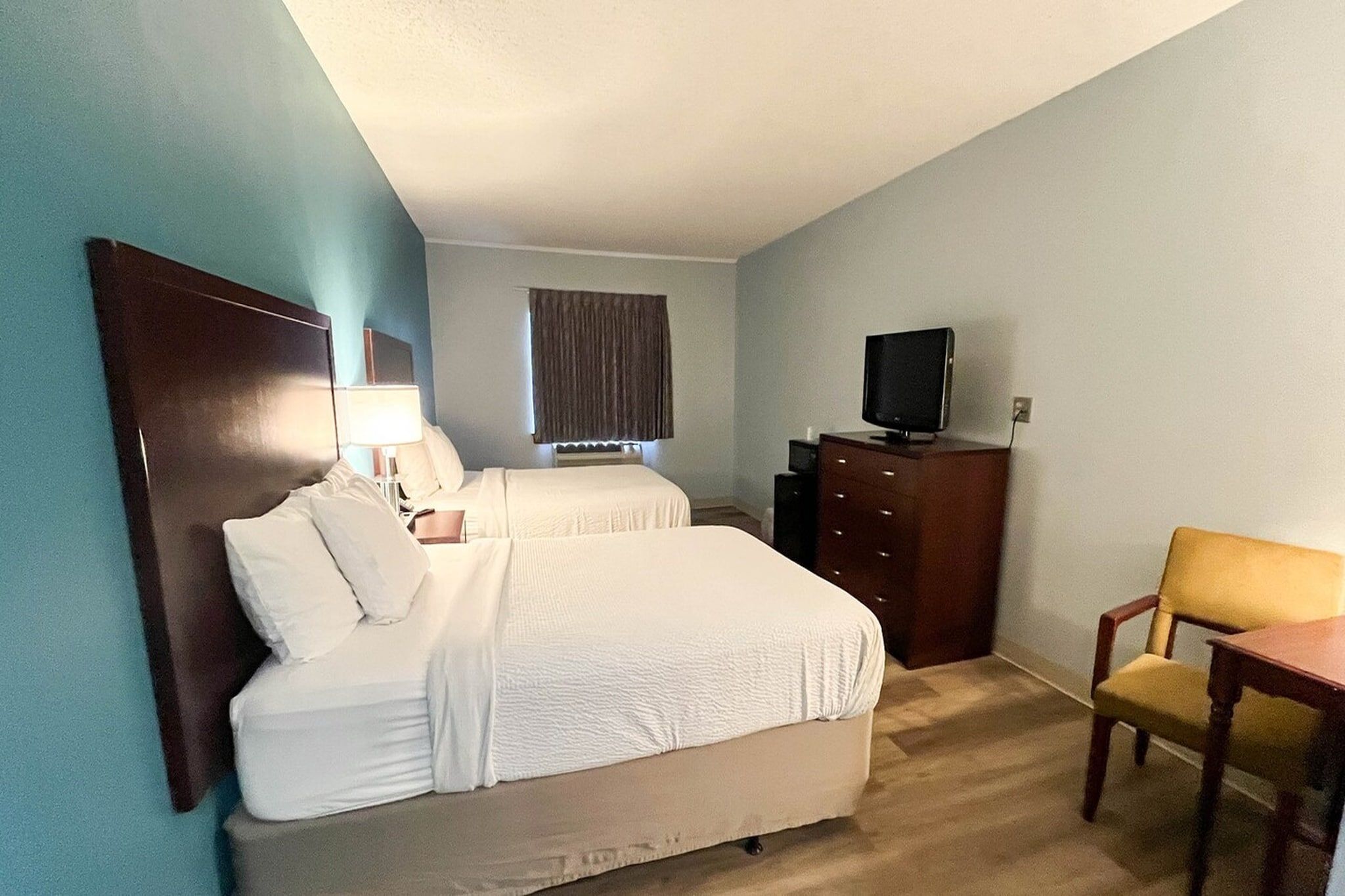 Ett hotellrum med två sängar, en tv, ett skrivbord och en stol.