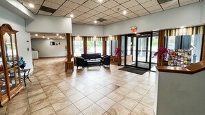A spacious lobby with a black sofa, a reception desk, and a glass door entrance.