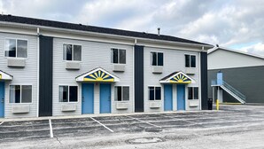 A motel with a row of rooms, each with a blue door and a sun emblem above the door.