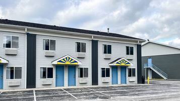 A motel with a row of rooms, each with a blue door and a sun emblem above the door.