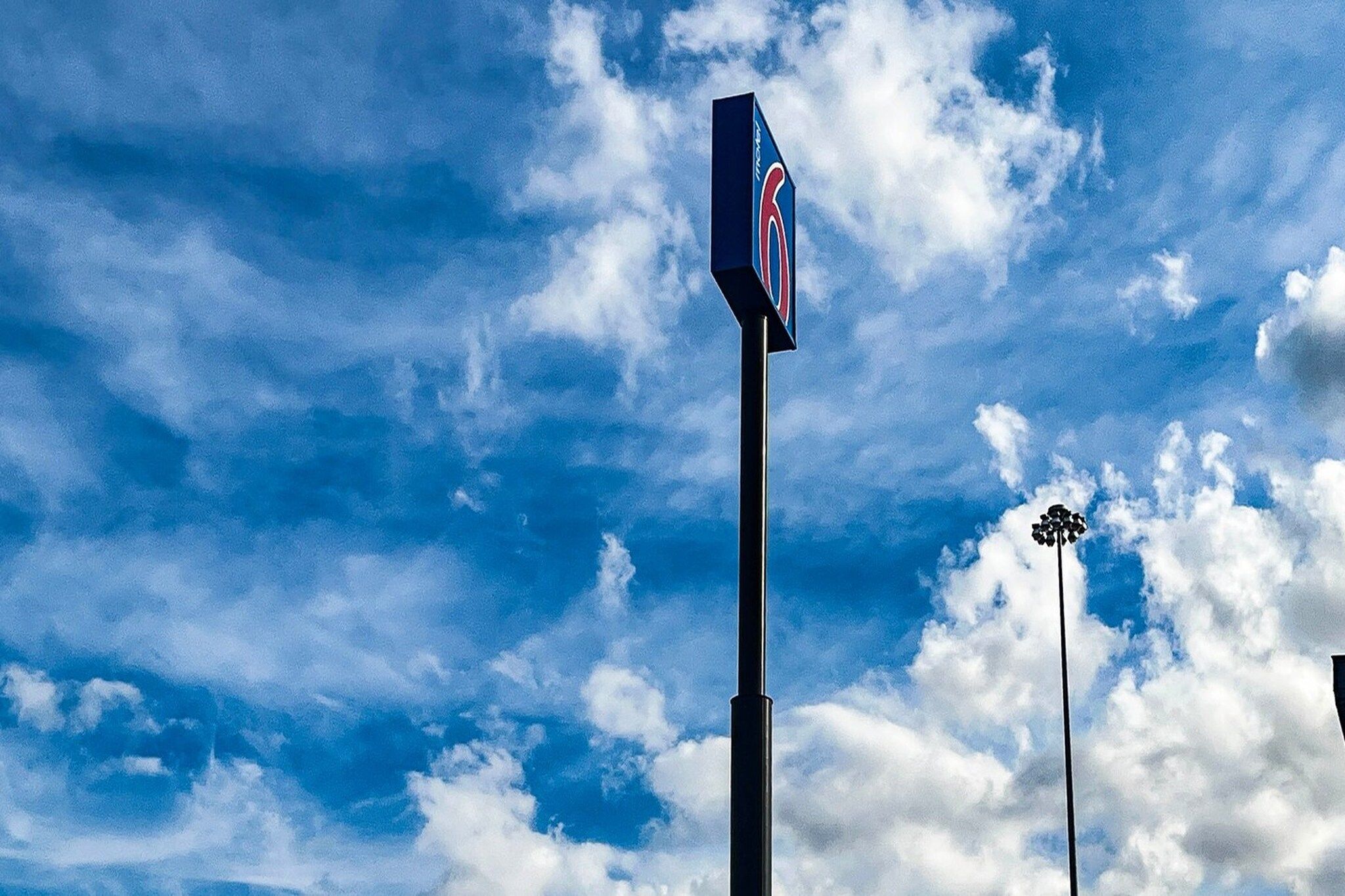 Cielo despejado con nubes y un cartel en un poste.