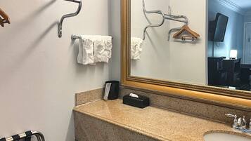 A bathroom with a granite countertop, a sink, a mirror, and towel racks.