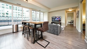 Una sala de estar moderna con comedor, ventanas amplias, televisor y sofá.