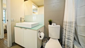 Un baño moderno con un lavabo de cristal, un inodoro y una cortina de ducha.
