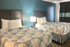 A hotel room with two beds, a bedside table with a lamp, and a window with curtains. - 2 Queen Beds | Non-Smoking, Micfridge (Lafayette LA)