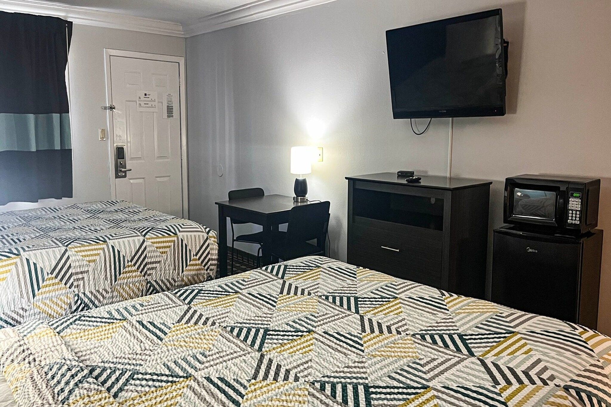 Quarto de hotel com duas camas, uma mesa, uma televisão e um micro-ondas.