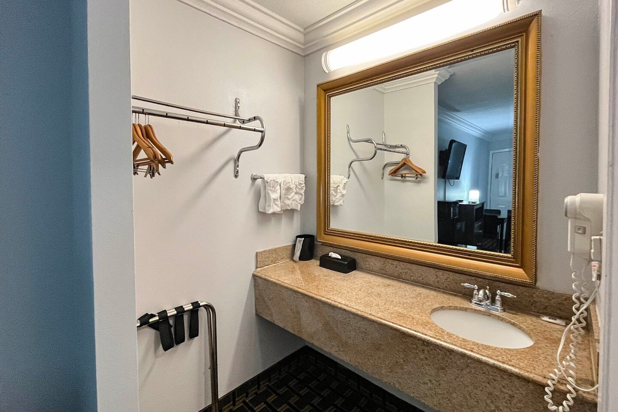 A hotel bathroom with a sink, mirror, towel rack, and a telephone.
