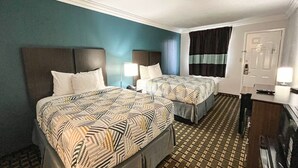 Quarto de hotel com duas camas, uma escrivaninha e uma porta.