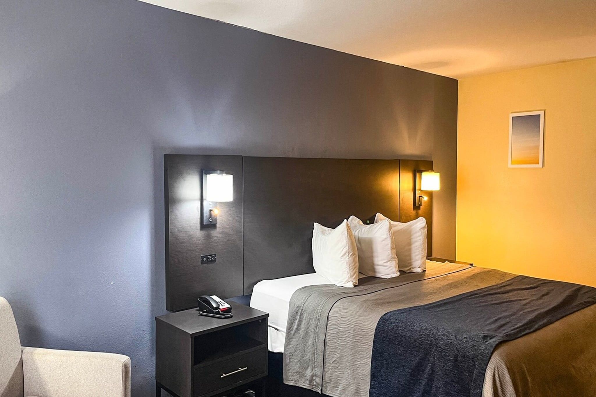 Ein Hotelzimmer mit einem Bett, einem Nachttisch und einer Wandlampe.
