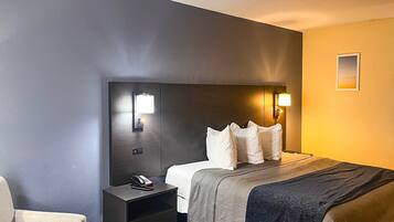 Ein Hotelzimmer mit einem Bett, einem Nachttisch und einer Wandlampe.