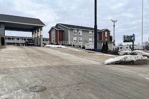 A parking lot with a gas station, a building with multiple windows, and a snow-covered ground.