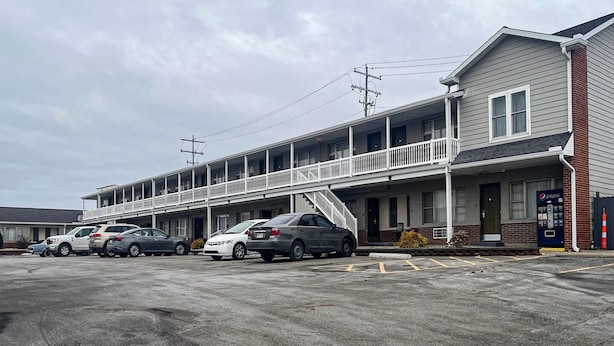 Um motel com estrutura em dois andares, área de estacionamento coberta e uma máquina de refrigerantes Pepsi.