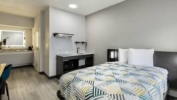 Quarto de hotel com cama, escrivaninha, toucador com espelho e mesa de cabeceira.