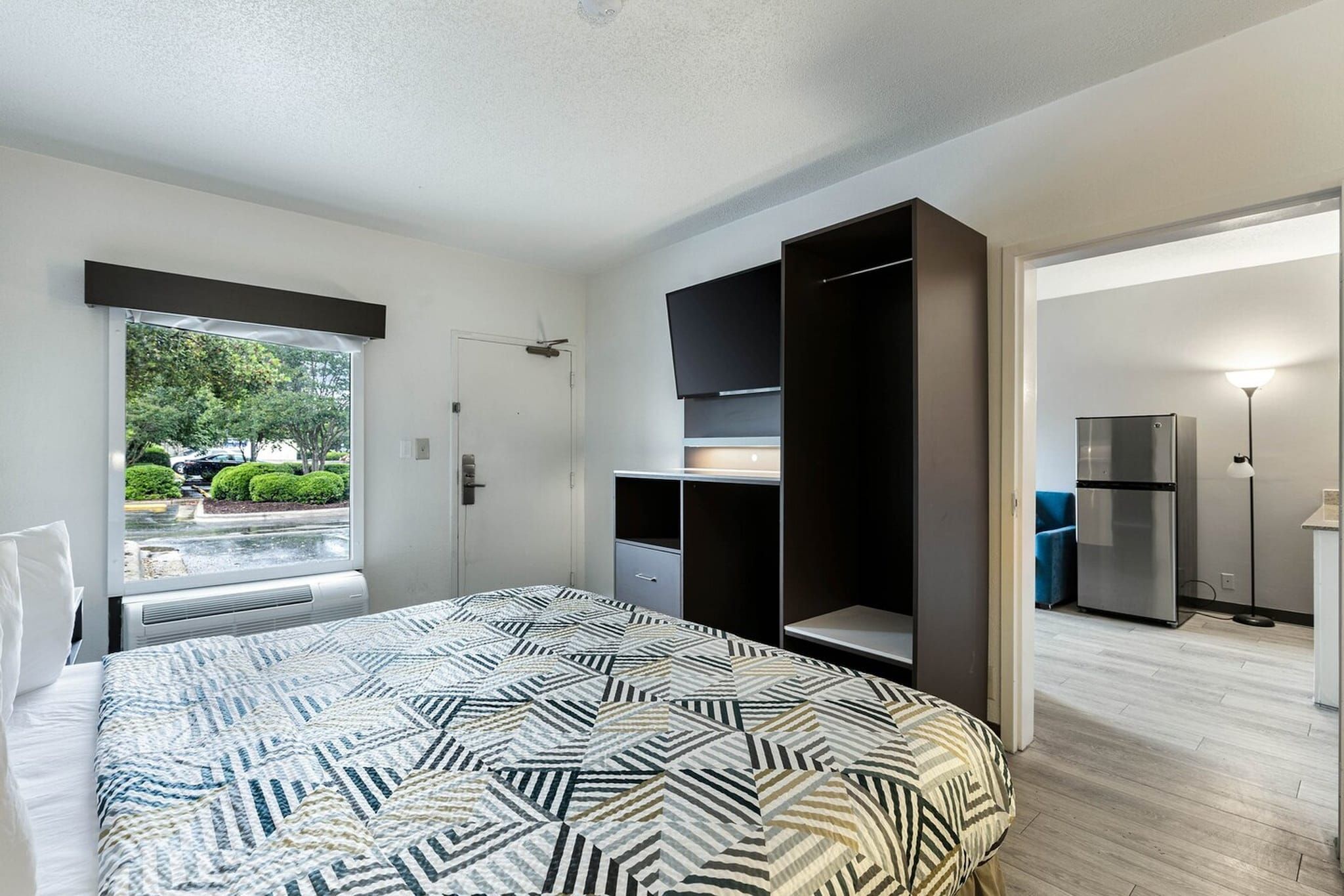 Une chambre à coucher comprenant un lit, une armoire, un téléviseur et un réfrigérateur.