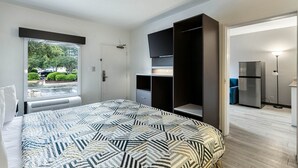 Une chambre à coucher comprenant un lit, une armoire, un téléviseur et un réfrigérateur.