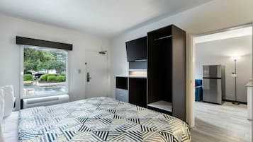Une chambre à coucher comprenant un lit, une armoire, un téléviseur et un réfrigérateur.