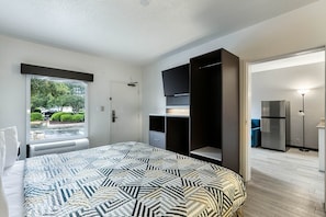Ein Schlafzimmer mit einem Bett, einem Kleiderschrank, einem Fernseher und einem Kühlschrank.