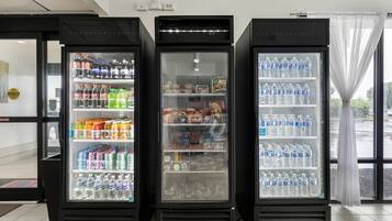 Três máquinas de venda automática com diversas bebidas e petiscos.