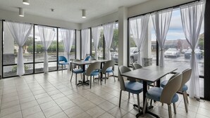 Une salle de conférence dotée d’une grande table et de chaises, de grandes fenêtres avec des rideaux et donnant sur un parking.