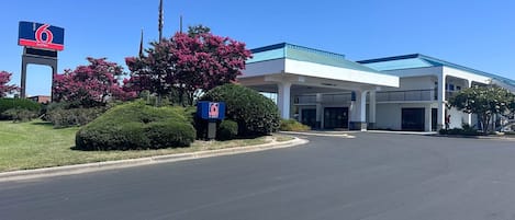 A hotel with a clear sky, a sign indicating 6 suites, and a building with a blue roof.