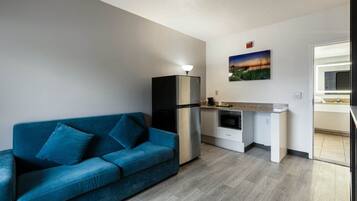 Um espaço compacto com cozinha compacta, um sofá azul e um quadro na parede.