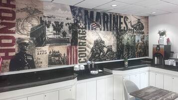 Interior de restaurante com um grande mural retratando cenas militares e as palavras 'MARINES' e 'Coragem'.