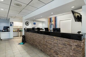 A reception area with a stone counter, a clock, and a wall-mounted TV.