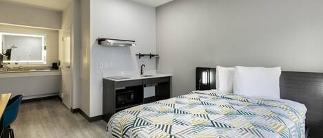 Une chambre d’hôtel comprenant un lit, un bureau, une coiffeuse avec un miroir et une table de chevet.