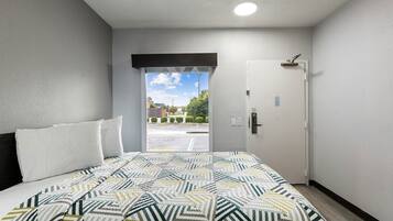 Quarto de hotel com cama, porta e vista para um estacionamento.