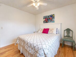 Ein Schlafzimmer mit Bett, Deckenventilator, Gemälde und Stuhl.