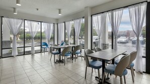 Une salle de conférence moderne, dotée d’une grande table et de chaises, de larges fenêtres avec des rideaux légers et donnant sur un parking.
